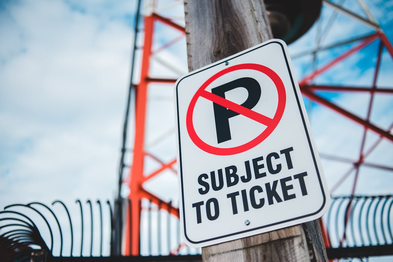 our-story Close-up of a no parking sign with a tower in the background, emphasizing traffic restrictions and warnings.
