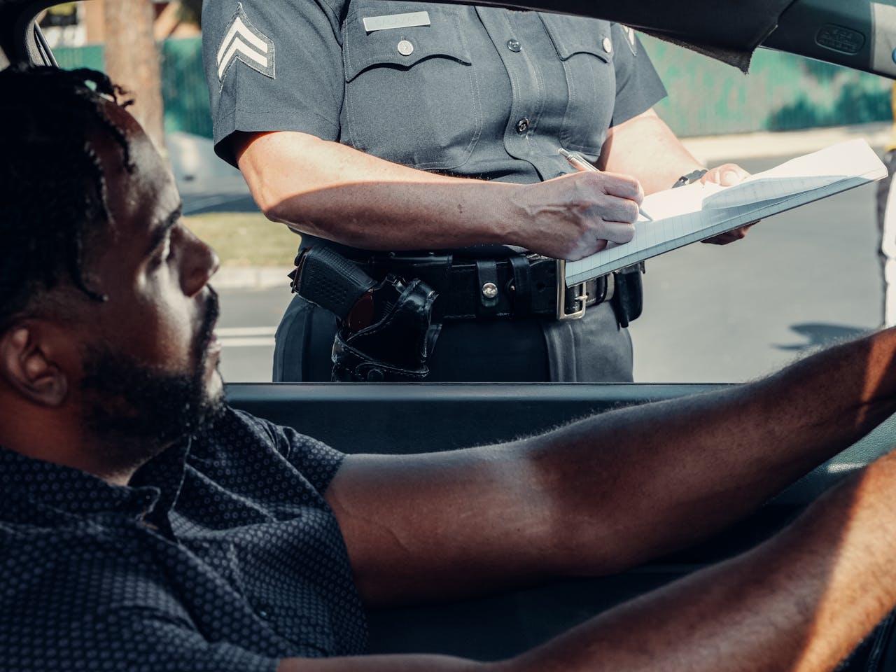 home-img A police officer issues a traffic ticket to a driver seated in a car during the day.